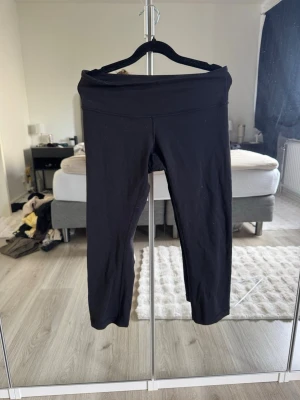 Svarta leggings med hög midja - Säljer ett par svarta leggings med hög midja och stretchigt material. De har en enkel, stilren design utan synliga loggor eller detaljer. Perfekta för en avslappnad look eller till träning. Passformen är tajt och materialet känns mjukt mot huden.