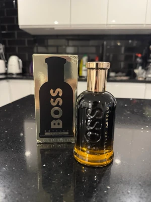 BOSS Bottled absolu 100ml - Stilren parfymflaska från BOSS med guldfärgat lock och svarttonad glasflaska. Flaskan har tydlig BOSS-logga och kommer med originalförpackning i metallic och svart. Doften är maskulin och elegant, perfekt för dig som vill sticka ut.