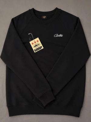 Corteiz HMP Crewneck - Svart crewneck sweatshirt från Corteiz med broderad vit logga på bröstet. Klassisk passform med ribbade muddar vid ärmslut och nederkant. Perfekt för en avslappnad streetwear-look. Priset är inte hugget i sten.