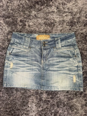Lowwaist vintage jeanskjol - Längd: 35 cm. Midja tvärsöver: 35 cm. Omkrets midja: ca 80 cm. Observera en liten fläck som förmodligen försvinner i tvätten, på bild 3🫶🏼❣️