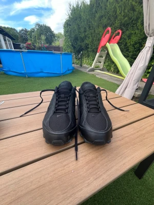 Svarta Nike sneakers i mesh och syntet - Snygga helsvarta Nike sneakers med ovandel i mesh och syntetmaterial. Klassisk låg modell med svart sula och svarta skosnören. Perfekta för dig som gillar stilrena och sportiga skor med diskret Nike-logga på sidan och tungan.