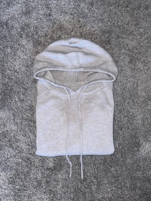 Ljusgrå kashmir hoodie - Säljer en enkel och stilren ljusgrå hoodie med huva och dragsnören. Hoodien har en klassisk passform och är tillverkad i mjukt material som passar perfekt för en avslappnad look. Perfekt basplagg till garderoben.