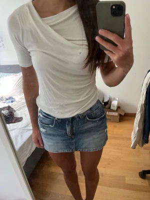 Vit omlott topp - Säljer en vit topp med omlottdetalj och kort ärm. Toppen har en asymmetrisk halsringning och är gjord i ett mjukt, stretchigt material, storlek Xs men skulle säga att den passar Xs-S❣️
