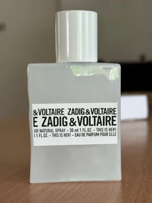 Zadig & Voltaire This Is Her! EdP 30ml - Parfymen This Is Her! från Zadig & Voltaire i en stilren, vit, fyrkantig flaska på 30 ml. Doften har noter av vanilj, vispad grädde, kastanj, sandelträ och jasmin. Flaskan är tillverkad i glas med minimalistisk design och svartvit etikett. Ungefär 60% kvar av parfymen💕