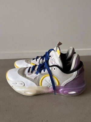 Li-Ning Way of Wade basketdojor - Säljer ett par Li-Ning Way of Wade basketdojor i vitt, gult och lila med blå skosnören. Skorna har meshpaneler, syntetmaterial och en chunky sula med cool gradient. Plösen har tryck och signaturdetaljer. Grymma för basket eller streetstyle. Storlek 43 2/2. Sjukt snygga. Några nötningar i tyget (se bilder).   Sök på modell ABAU015-14 för att läsa mer om modellen.