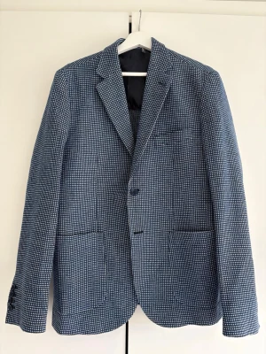 Blåvit mönstrad kavaj - Blå/vit/svart rutig kavaj i ull material. Supersnygg på sommaren till en par ljusa jeans. Använd 2 gånger! 