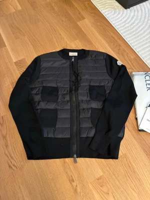 Svart cardiganjacka från Moncler - Säljer vidare min moncler cardigan jacka i nyskick. Knappt kommit till användning.  Storlek L men passar bättre på en M då den är lite mindre i storlek.  Skickas med sin dust bag. 