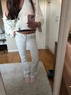 Vita bootcut jeans med låg midja - Säljer ett par vita bootcut jeans med låg midja och med en snygg mörk söm. Jeansen har klassisk femficksdesign och är tillverkade i ett stretchigt denimtyg som sitter perfekta. Jeansen är i nyskick. 