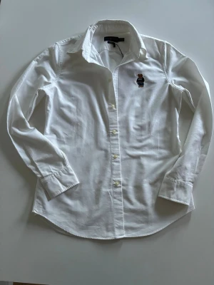 Ralph lauren skjorta - Vit Ralph lauren skjorta Slim fit i storlek M. Den har 2 små slitningar som inte är så tydliga men är värda att poängtera(skriv för bild) annars har den använts ett fåtal gånger i och med att den är för liten för mig. Passar mer S enligt min bedömning även om storleken är M, kom gärna privat för mått eller andra funderingar!