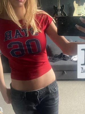 Röd topp Subdued - Snygg röd croppad topp från det trendiga märket Subdued.  Blå text 'STAR 06' framtill och backless. T-shirten har korta ärmar och tight passform, perfekt för en trendig look. Materialet känns som bomull och toppen har en klassisk rund halsringning. Storlek M men passar även  S💕