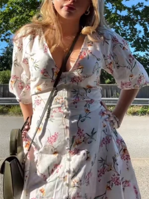 Vit blommig klänning med knappar - INTRESSEKOLL! Jätte söt sommar klänning från H&M med blommor på. Klänningen har djup v-ringning, knappar framtill och trekvartsärm. Andvänt ett par gånger! 