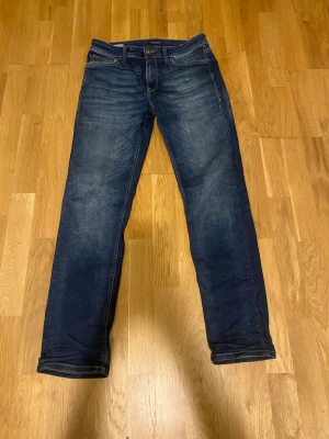 Mörkblå jeans Regular Clark från Jack n Jones  - Säljer ett par mörkblå jeans i modellen Regular Clark. Jeansen har klassisk femficksdesign, raka ben och snygga slitningar framtill. Materialet är denim med kontrastsömmar. Perfekta för en avslappnad och stilren look.