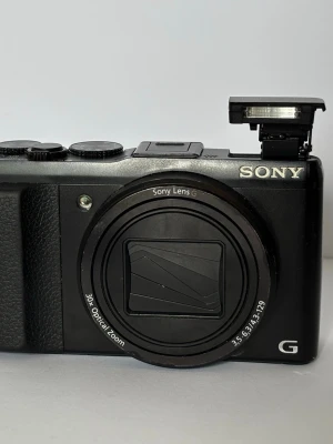 Sony DSC-HX50  - Kompakt digitalkamera med 30x optisk zoom. Kameran har en utfallbar blixt och flera inställningsmöjligheter för fotografering. Pà baksidan finns en skärm och knappar för menynavigering samt inspelning. Kameran är svart. Bra för att ta trendiga "tiktok bilder" Jag har inget batteri till kameran så kan inte garantera 100% funktion
