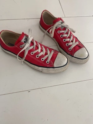 Röda Converse All Star låga sneakers - Klassiska röda Converse All Star sneakers med vit tå och vita snören. Skorna har lågt skaft, canvasmaterial och gummisula. Ikonisk design med svarta och vita detaljer samt metallöljetter för snörningen. Perfekta för en avslappnad och cool stil. Säljs för att jag köpt dem second hand med de var fel storlek☹️jätte snygga!!