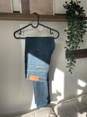 Blå jeans från Acne Studios - Säljer ett par klassiska blå jeans från Acne Studios. Jeansen har fem fickor, raka ben och snygga kontrastsömmar. Tillverkade i slitstarkt denim med en läderpatch bak i midjan. Perfekta till alla dina outfits!