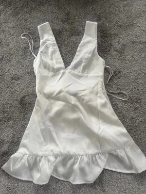 Vit kort klänning med rosett - Jättefin klänning från Hello Molly, aldrig använd och prislappen är kvar, kostar 900kr plus frakt 213kr. Skickas tillbaka om den inte säljs