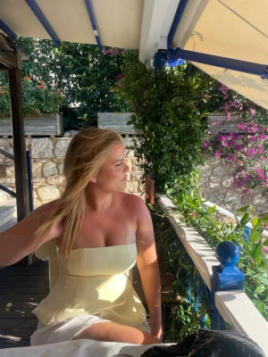 Ljusgul axelbandslös tubtopp - Trendig ljusgul axelbandslös tubtopp med bandeau-form och figurnära passning. Perfekt för varma dagar och somriga outfits. Toppens material känns mjukt och lätt, vilket gör den bekväm att bära hela dagen.