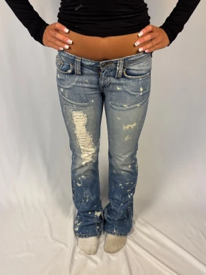 Lågmidjade Jeans - Lågmidjade Jeans med färgstänk och distressing  | Size: 26 | Väldigt bra skick, inga defekter | Modellen på bilderna är 168cm lång och väger 60kg | Mått: Ytterbenslängd: 105cm. Midjebredd: 39cm. Lårbredd: 27cm. Fotöppning: 24cm. Kontakta mig vid fler frågor eller funderingar!