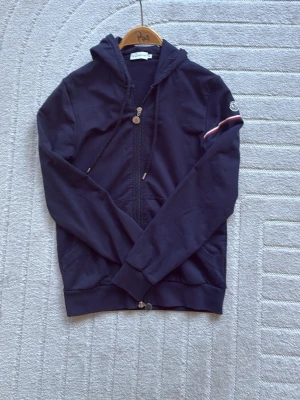  zip hoodie Moncler - Snygg mörkblå zip hoodie från moncler. Tillverkad i mjuk bomullstyg. Denna modell är SLIM så ha det i åtanke ifall ni är intresserade. Den är så klart äkta och köpt från von greven closet, ifall du har några frågor så är det bara meddela mig! 