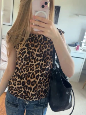 Leopardmönstrad ärmlös topp - Säljer en snygg ärmlös topp med leopardmönster toppen  är i ett mjukt, lätt material som passar perfekt till jeans eller kjol. 