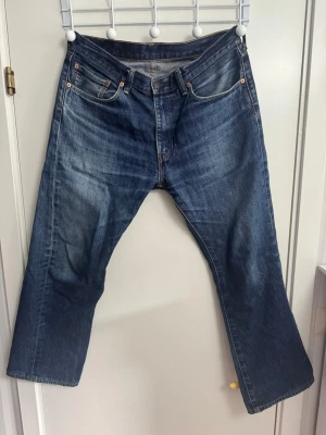 Levi's 505 raka blå jeans - Klassiska blå Levi's 505 jeans med rak passform och fem fickor. Jeansen har tydliga kontrastsömmar, gylf med dragkedja och den ikoniska läderpatchen bak i midjan. Tillverkade i slitstark denim med snygg tvätt och vintagekänsla. Superskick!