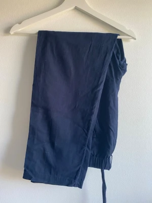 Mörkblå linnebyxor Uniqlo M  - Snygga mörkblå linnebyxor med avslappnad passform. Byxorna har resår bak, fickor i sidorna och är tillverkade i ett lätt och luftigt linnematerial. Perfekta för en stilren look.