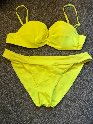 Gul bikini med bygel och axelband - Snygg gul bikini med vadderad bygel-bh och justerbara axelband. Klassiska bikinitrosor med bred linning. Perfekt för stranden eller poolen, ger en färgstark look. Överdel i 75b och underdel  i s