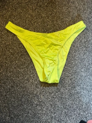 Gula bikiniunderdelar i syntet - Snygga gula bikiniunderdelar i klassisk modell med hög benskärning. Tillverkade i ett stretchigt syntetmaterial som sitter bekvämt och följer kroppen. Perfekta för strandhäng eller poolen.