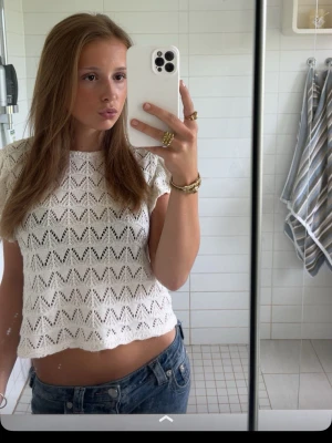 Vit virkad topp från Gina Tricot - Superfin vit virkad topp från Gina Tricot med korta ärmar och snyggt hålmönster. Toppen är croppad och har en luftig känsla, perfekt till jeans eller kjol. Enkel att styla och ger en fräsch look.