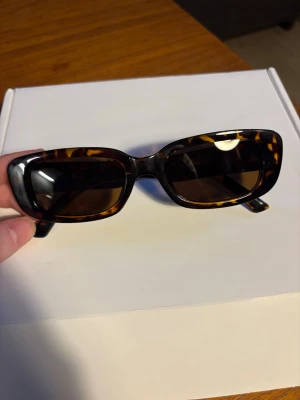 Bruna rektangulära solglasögon Eyekonik - Helt nya! Snygga solglasögon från Eyekonik med rektangulär form och brunmelerat sköldpaddsmönster på bågarna. Säljer då dem är för stora för mig. 