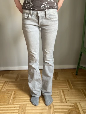 Ljusgrå bootcut jeans från Gina Tricot - Säljer ett par ljusgrå jeans från Gina Tricot med bootcut passform och klassiska fem fickor. Jeansen har låg midja och är tillverkade i ett mjukt denimtyg. Snygga kontrastsömmar och diskret logga på bakfickan. 💕