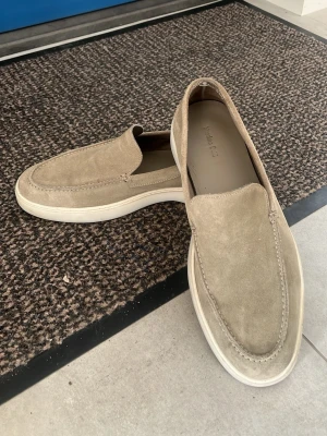 Beige mocka loafers från Massimo Dutti - Säljer ett par stilrena loafers i beige mocka från Massimo Dutti. Skorna har en klassisk slip-on design med vit sula och diskreta sömmar längs ovandelen. Perfekta för dig som gillar en clean och avslappnad look. 849kr. Man fick inte med box vid köp, endast dustbags så det tillkommer 