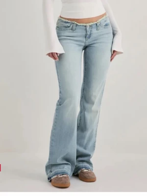 Ljusblå bootcut jeans med rå kant - Säljer ett par ljusblå bootcut jeans från Nelly  med låg midja och rå, fransad kant upptill. Använt typ en gång då dom är alldeles för långa för mig❤️