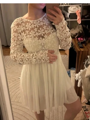Studentklänning❤️ - Superfin vit klänning med långärmad överdel i blommig spets( inbyggd bh) och rund halsringning. Kjolen är lätt och faller snyggt i chiffongliknande material. Perfekt för student eller midsommar! Öppen rygg för extra detalj. Perfekt till studenten❤️Ca 1.60 för referens😊