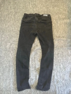 Svarta jeans Tommy Hilfiger - Ett par svarta skinny jeans/slim fit från Tommy Hilfiger. Storlek 164 (barn). Hör bara av er vid frågor! 