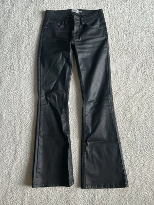Svarta skinn-byxor  - Snygga svarta coated skinnbyxor från lager 157 med bootcut-modell. Byxorna har fem fickor, hällor för skärp och en glansig finish som ger en cool look. Perfekta för dig som vill ha ett par trendiga byxor med lite extra edge. Original pris 300, för fler bilder kom privat💞