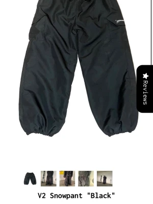 Svarta täckbyxor från Powderwear - Säljer ett par svarta täckbyxor från Powderwear med bred passform och resår i benslut. Byxorna har praktiska fickor på sidorna och är tillverkade i slitstarkt, vattenavvisande material. Perfekta för kalla dagar i backen eller vinterpromenader.