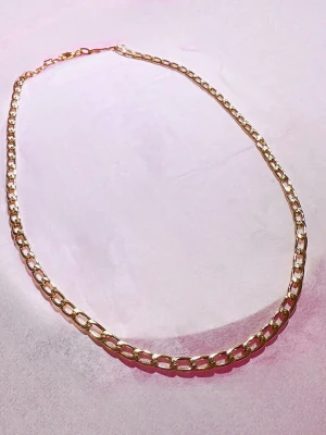 Guldfärgat kedjehalsband Rostfrittstål  - Snyggt halsband i guldfärg med breda, platta länkar som ger en trendig och stilren look. Perfekt att bära som statement-piece till olika outfits. Halsbandet har ett klassiskt karbinlås och är tillverkat i rostfrittstål