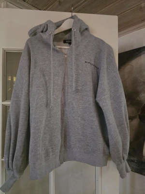 Grå zip hoodie oversized från Missguided - Snygg grå hoodie från Missguided med dragkedja framtill och justerbar huva med snören. Hoodien har en relaxed fit och ribbade muddar vid ärmslut och nederkant. Perfekt för en chill och avslappnad stil.