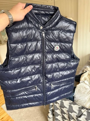 Moncler Gui Väst - Säljer denna snygga Moncler Gui västen i storlek 4, skick 10/10, passar dig som är 180-190. Kom gärna med bud och frågor!