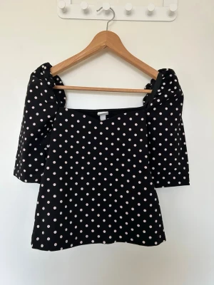 Svart prickig topp med puffärm - Svart topp med rosa prickar och puffärmar. 