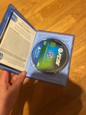 EA Sports FC 26 till PS4 - Säljer spelet EA Sports FC 26 till PlayStation 4. Omslaget är blått och spelet kommer i ett klassiskt plastfodral med färgglad framsida som visar fotbollsspelare. Perfekt för dig som gillar fotbollsspel och vill ha det senaste från EA.