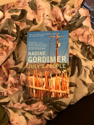 July's People av Nadine Gordimer Engelska 7  - Säljer boken 'July's People' av Nadine Gordimer. Pocketbok med blå och orange omslag, motiv av elstolpe och trästaket. Texten är på engelska och boken ges ut av Bloomsbury. Perfekt för dig som gillar samhällsskildringar och modern litteratur. Är på listan av böcker att välja under kursen engelska 7.