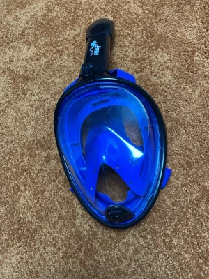 Blå helmask snorkel Red Sea Reef - Säljer en blå helmask snorkel från Red Sea Reef. Masken har ett stort visir i plast och integrerad snorkel upptill. Justerbara remmar i blått för bra passform. Perfekt för snorkling och undervattensäventyr.