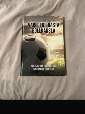 Världens bästa bollkänsla bok - En inspirerande bok med hårdpärm om bollkänsla och hur hjärnan påverkar oss i avgörande ögonblick. Omslaget har en fotboll och en solnedgång på en gräsplan. Perfekt för dig som gillar sport och psykologi.