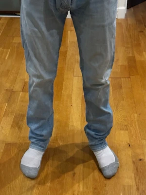 Blåa Jacob cohen jeans - Ljusblå jeans från Jacob Cohen, modell Style ”622”, i storlek W36. Jeansen är i bra skick, förutom ett litet hål som enkelt kan sys och en missfärgning på baken som eventuellt går bort vid starkare behandlingar. Personen på bilden är cirka 180 cm som referens för passformen. Nypris ligger på 5000 kr. Måtten är: midjemått 46 cm och längd 110 cm.