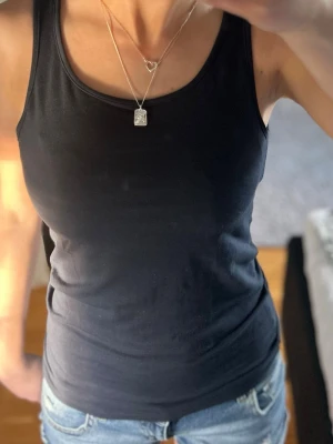 Svart linnetopp i bomull - Säljer ett enkelt och stilrent mörkblå linne med rund halsringning. Perfekt basplagg med tight passform som framhäver figuren. Snyggt att matcha med jeans eller kjol för en clean look. Materialet känns mjukt och bekvämt mot huden. Storlek 158/164 från H&M men skulle säga att de passar en xs eller liten s💕 Pris kan diskuteras såklart