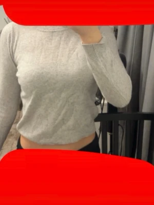 Ljusgrå stickad tröja med flätmönster - Säljer en ljusgrå stickad tröja med lång ärm och ett snyggt flätmönster på ärmen. Tröjan har en enkel, klassisk design och är mjuk och skön. Perfekt till jeans eller kjol för en avslappnad look.