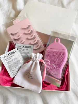 Presentbox - Skönhetskit  - Ett skönhetskit med rosa silikonborste för ansikte och hår, flera par lösögonfransar i naturstil, samt handkräm och body lotion från L:A BRUKET. Allt levereras i en snygg presentförpackning och med en vit tygpåse från Glow:id🩷