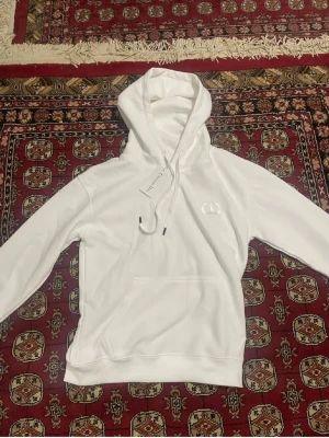 Vit christian d*ior hoodie  - S/XS Snygg vit hoodie från cristian d med klassisk huva och dragsnören. Hoodien har en diskret logga på bröstet och en stor magficka framtill. Tillverkad i mjukt material som känns skönt mot huden. Perfekt för en avslappnad och stilren look.